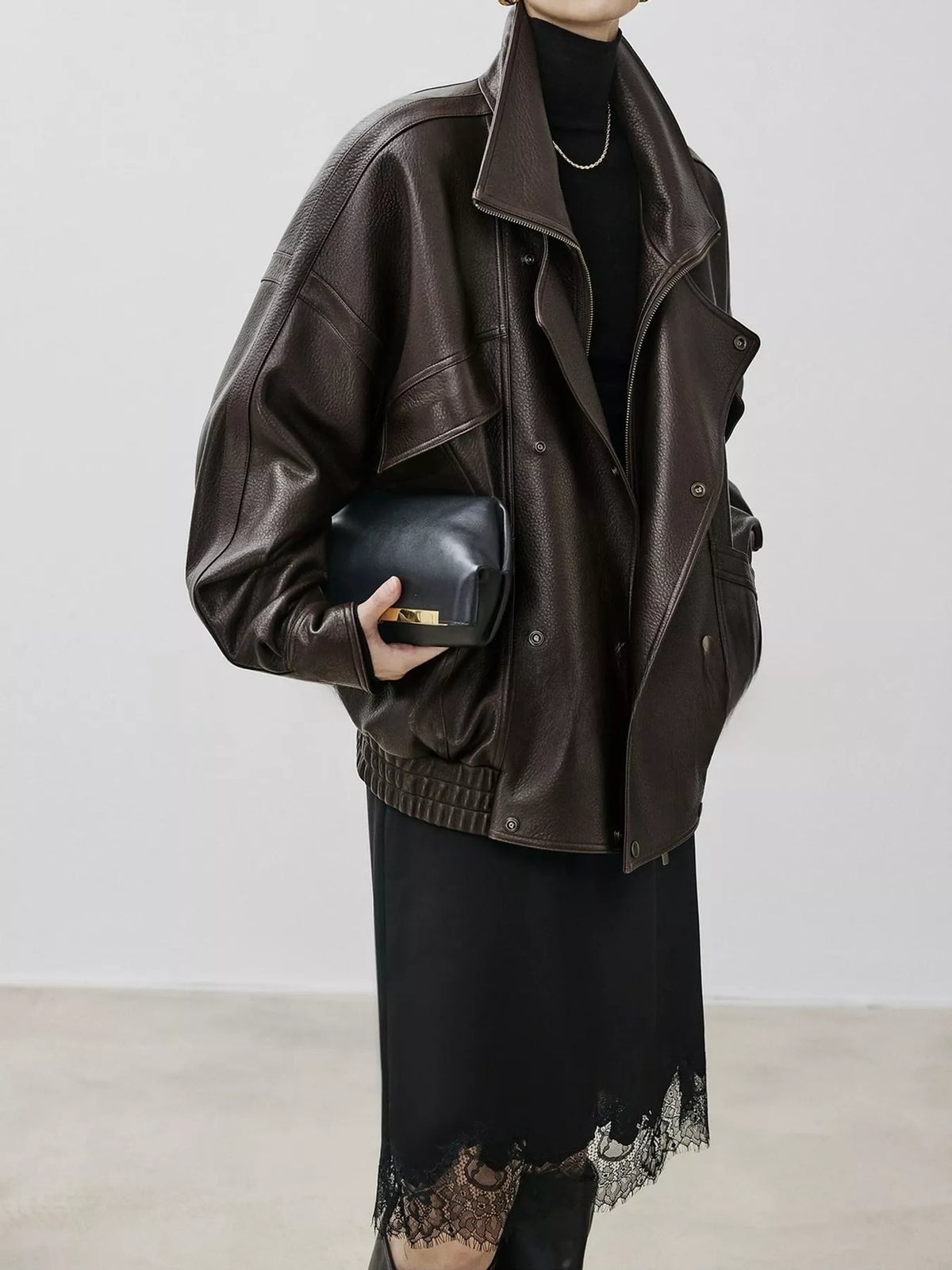 Black leather jacket with high collar, buttoned front, ribbed hem, side view