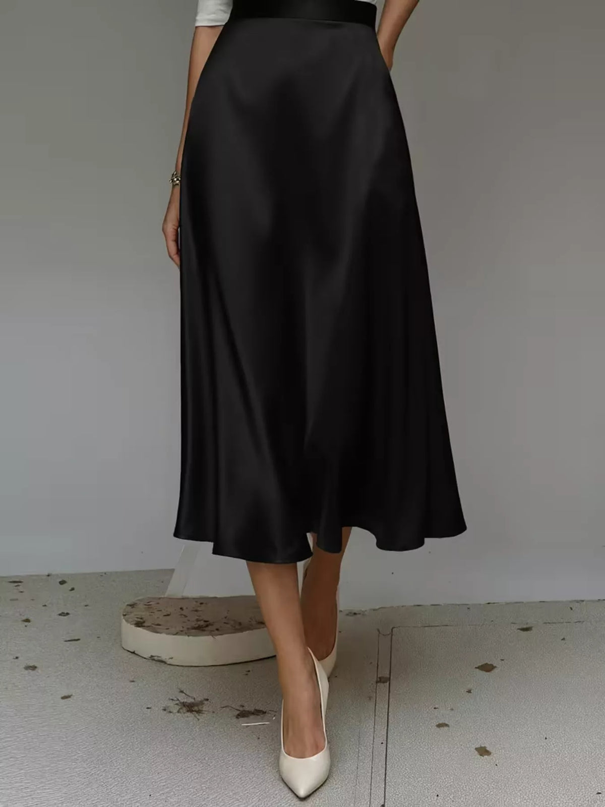 Back view of a black satin midi skirt with a high waist and A-line hem.