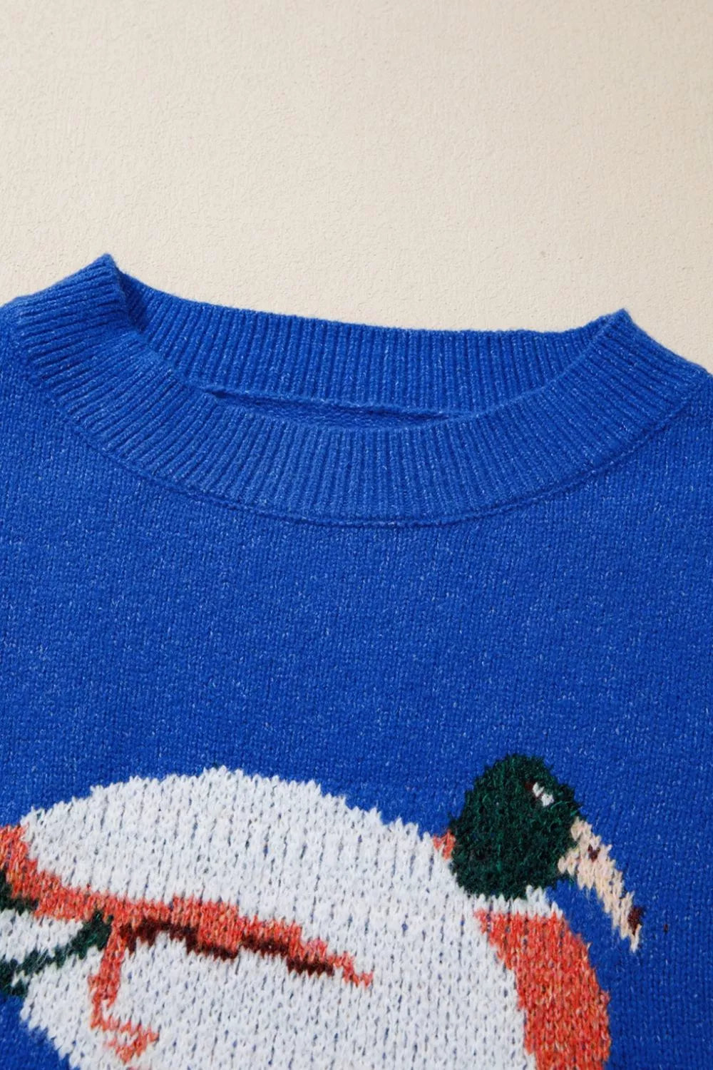 Royal blue sweater close-up of crew neck and duck graphic with orange details