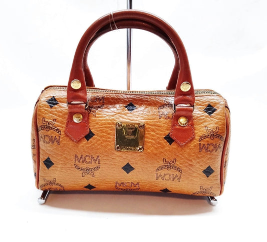 Brown mini Boston bag with leather handles, front metal logo plaque, and monogram print