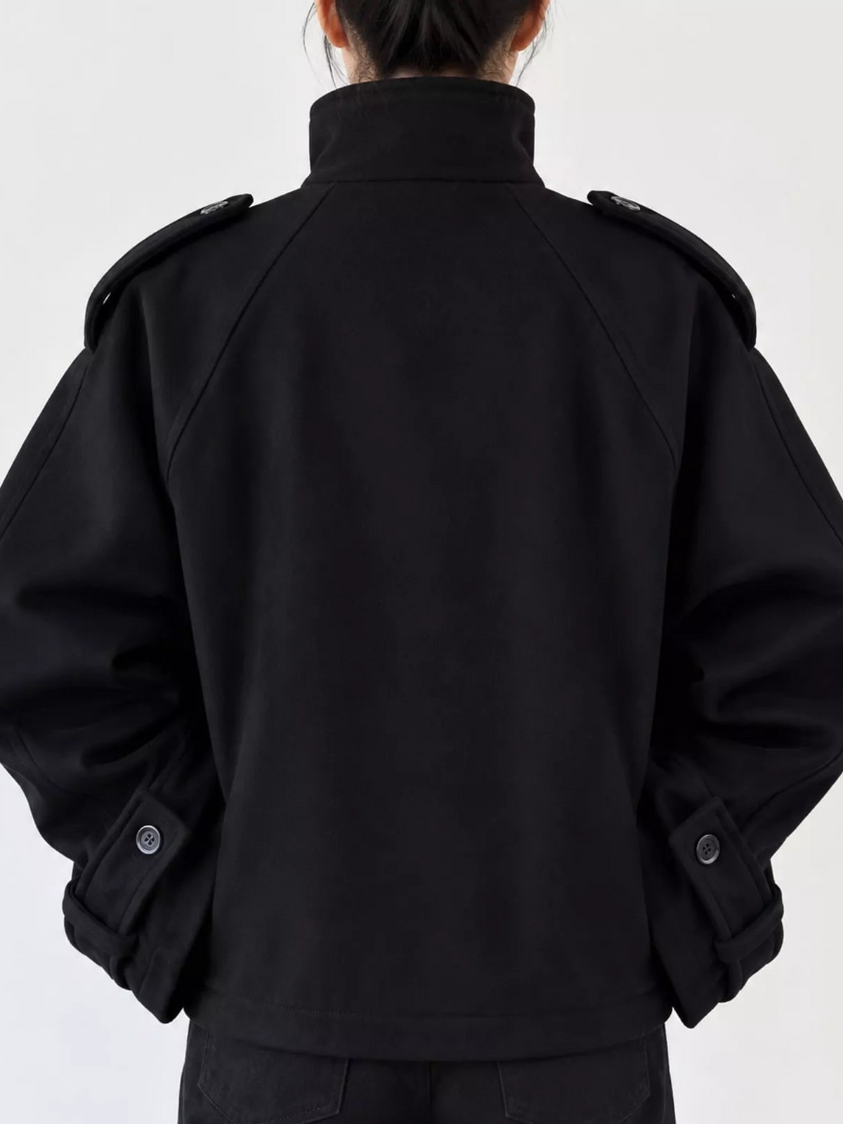 Black stand-collar zip-up jacket, back view with shoulder tabs and snap cuffs.