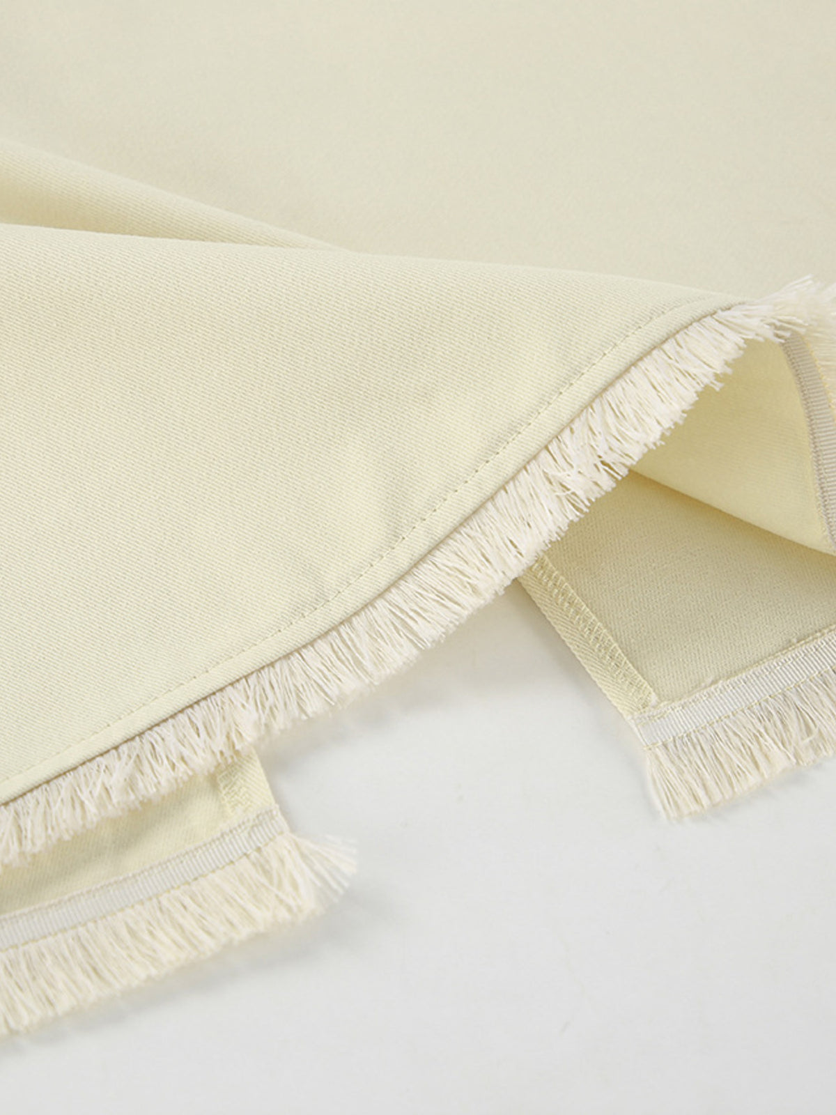 Beige slit midi skirt hem close-up with fringed edges and finished stitching.