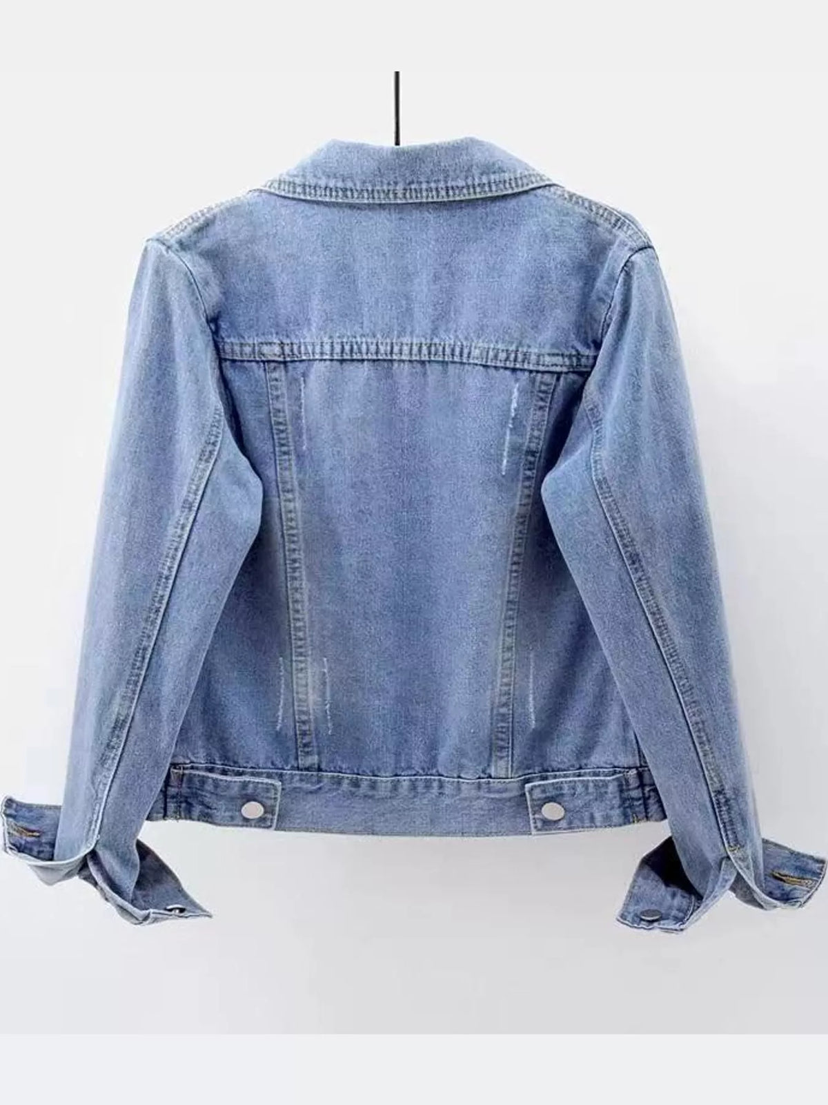 Light wash denim jacket back view with yoke seams and buttoned hem