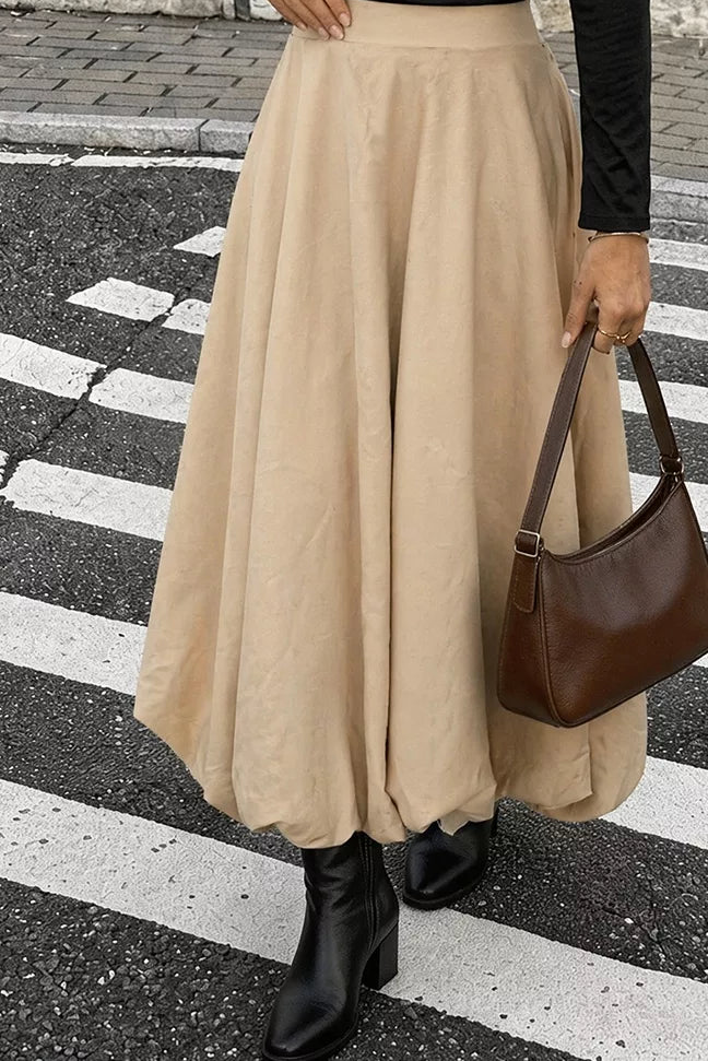Front view of the tan A-line skirt with a broad waistband and full midi-length skirt.
