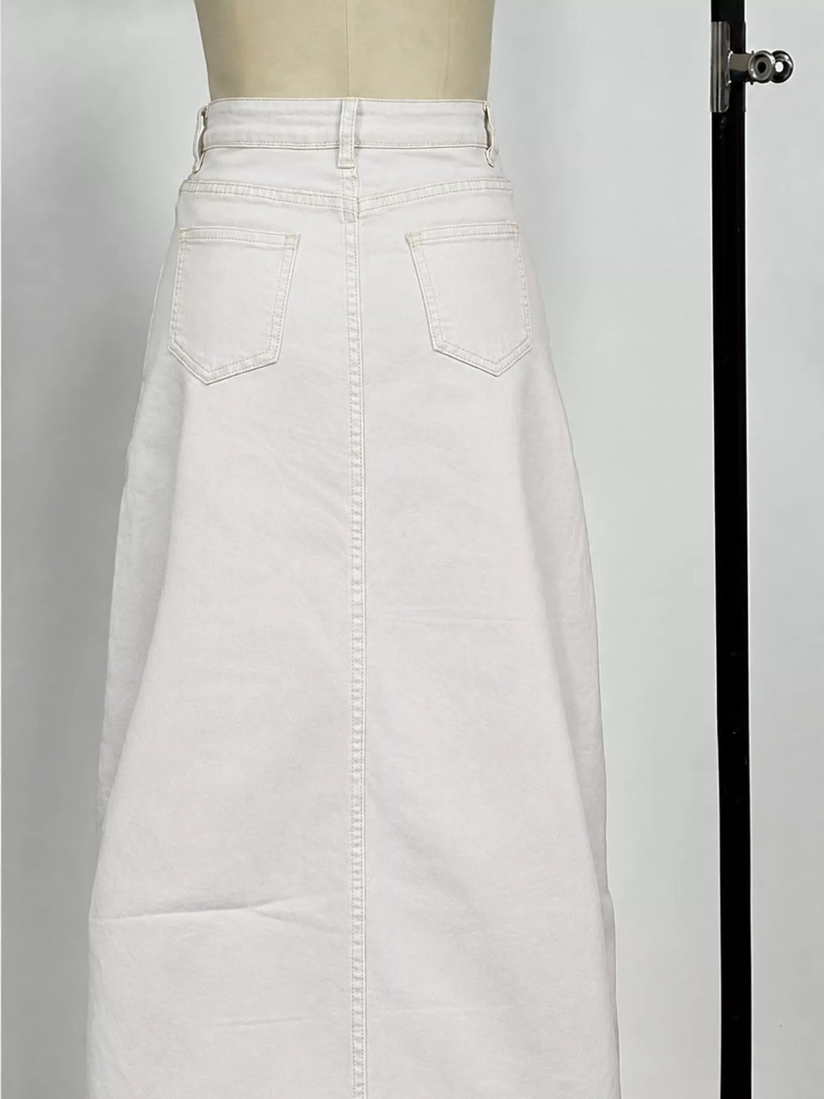 White denim maxi skirt close-up with two front pockets and center seam stitching