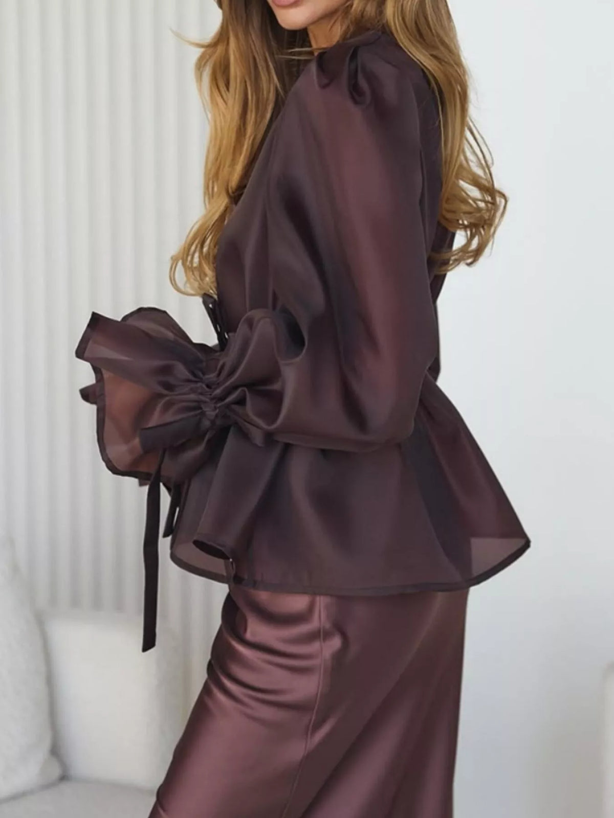 Dark brown set in side view, showing the blouse's peplum hem and satin midi skirt