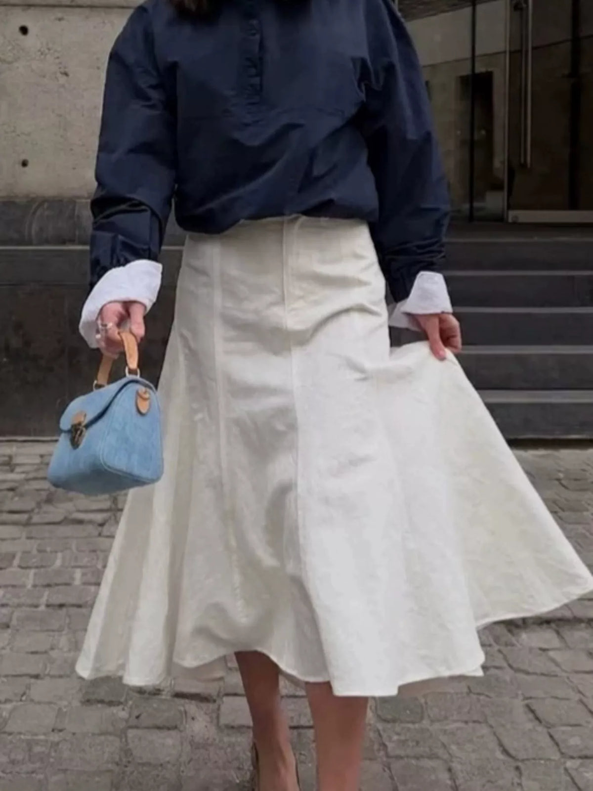White flared midi skirt with a high waist and front seams, shown on a model