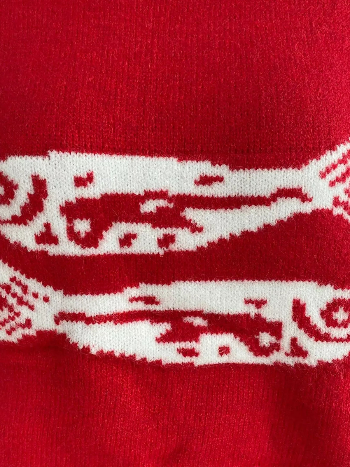 Close-up of red knit sweater with white fish graphic stripe