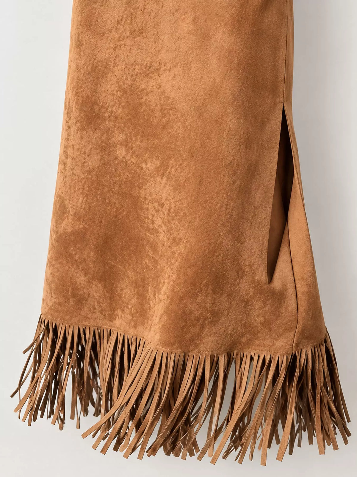 Close-up of the light brown skirt's side slit and long fringe hem