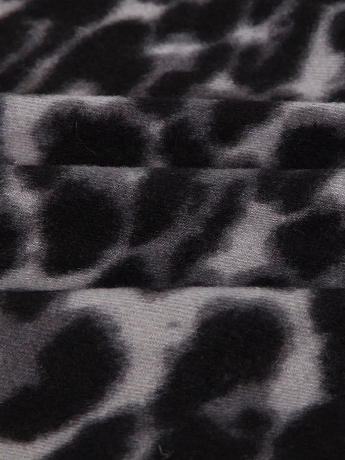 Black leopard print scarf fabric with gray spot pattern, soft woven texture.