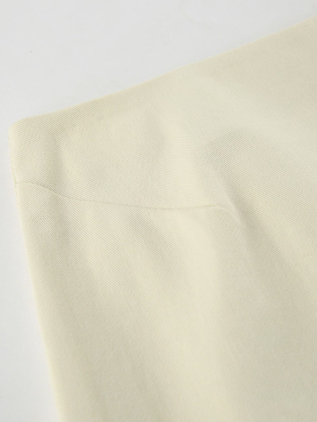 Beige skirt fabric close-up showing fine diagonal texture and a seam.
