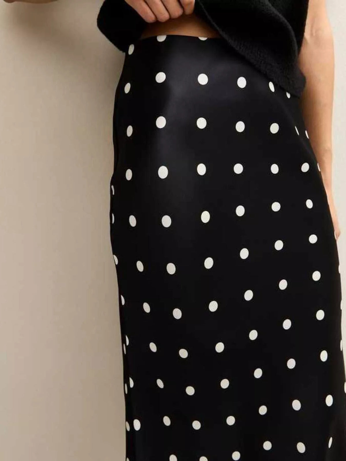 Close view of the black skirt's white polka dot pattern and fitted waist.