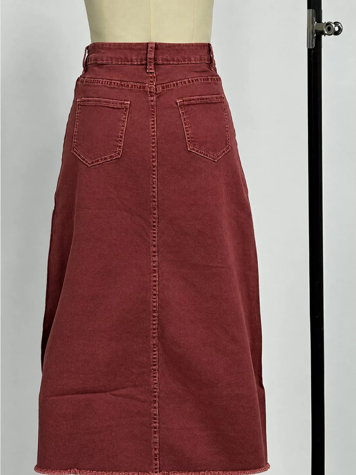 Burgundy denim maxi skirt close-up: double pockets and raw frayed hem