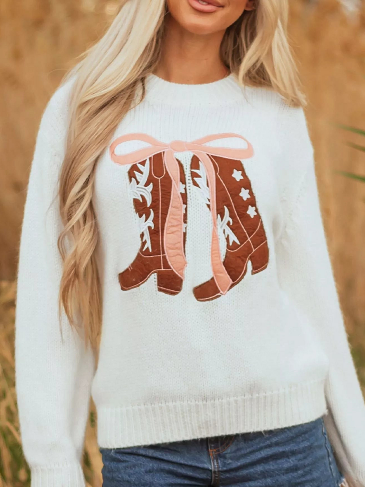 White knit sweater featuring an embroidered bow boots graphic on the front