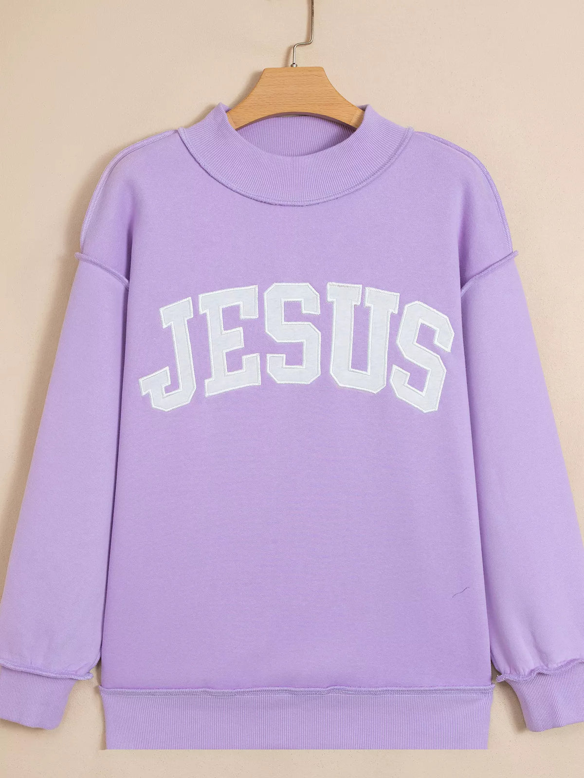 Lavender mock-neck sweatshirt on hanger with 'JESUS' front graphic