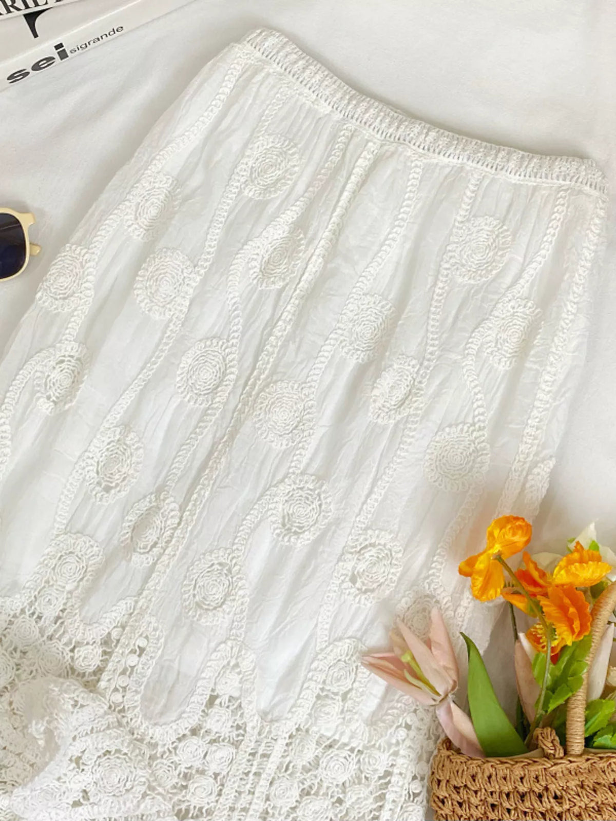 Close view of white skirt's elastic waist and embroidered lace panels