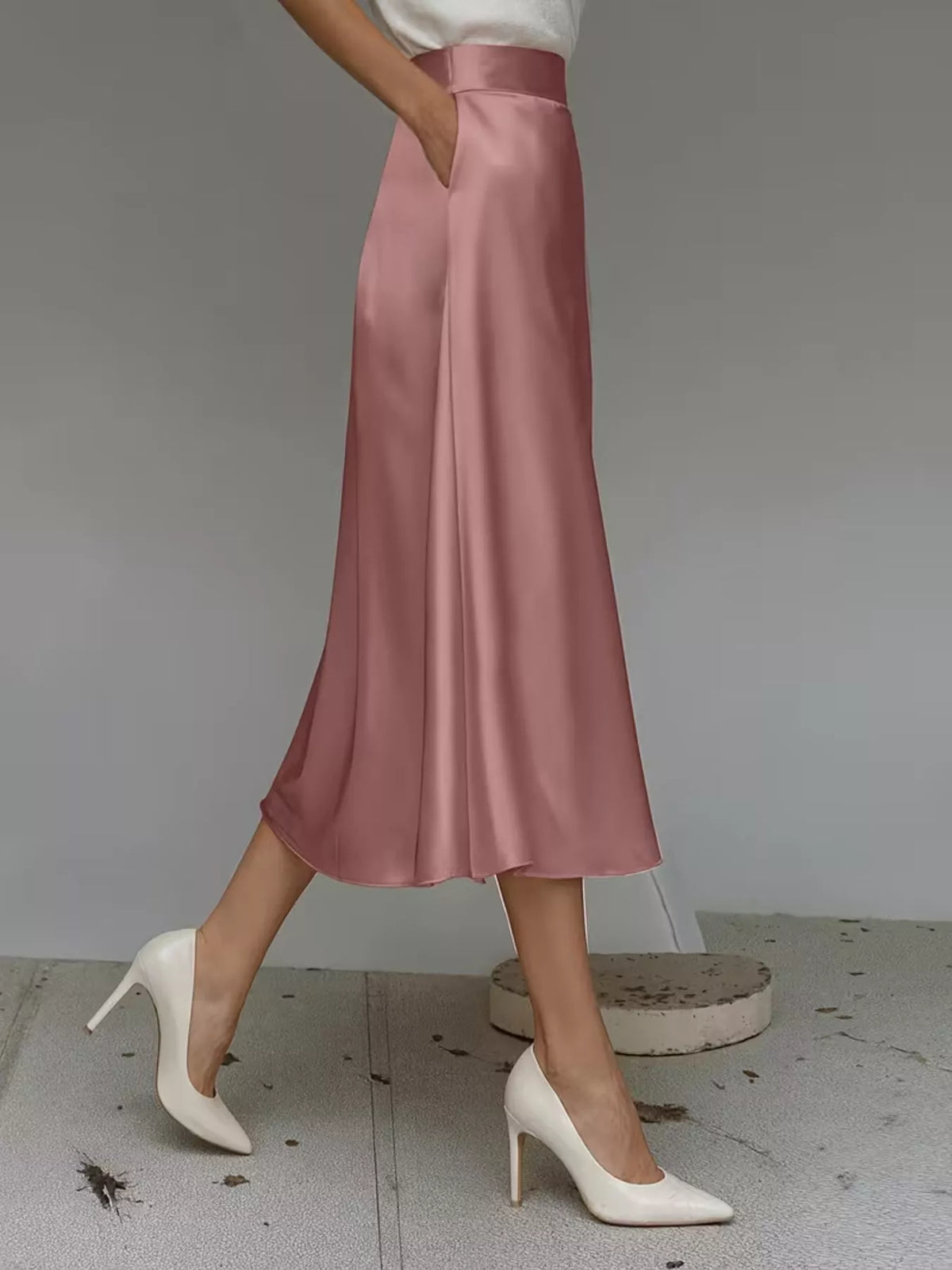 Pink satin midi skirt with a high waist, flowing A-line cut, and side pocket.