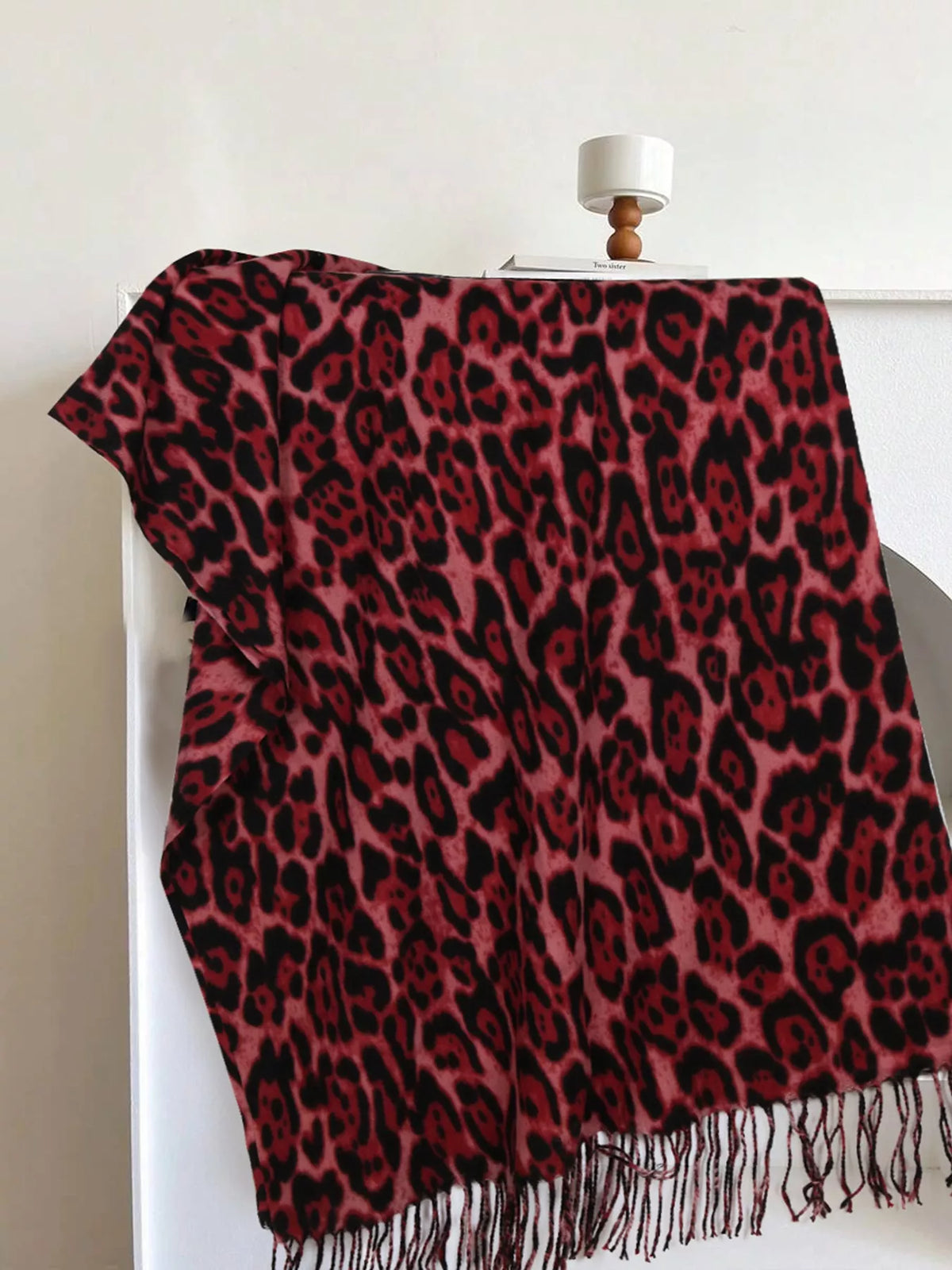 Rose red leopard print scarf with dark spots and long fringe along one edge.