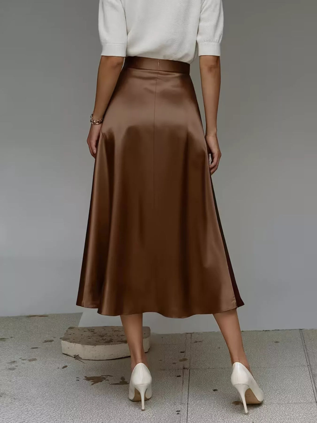 Back view of a dark brown satin midi skirt with a wide, flared hem