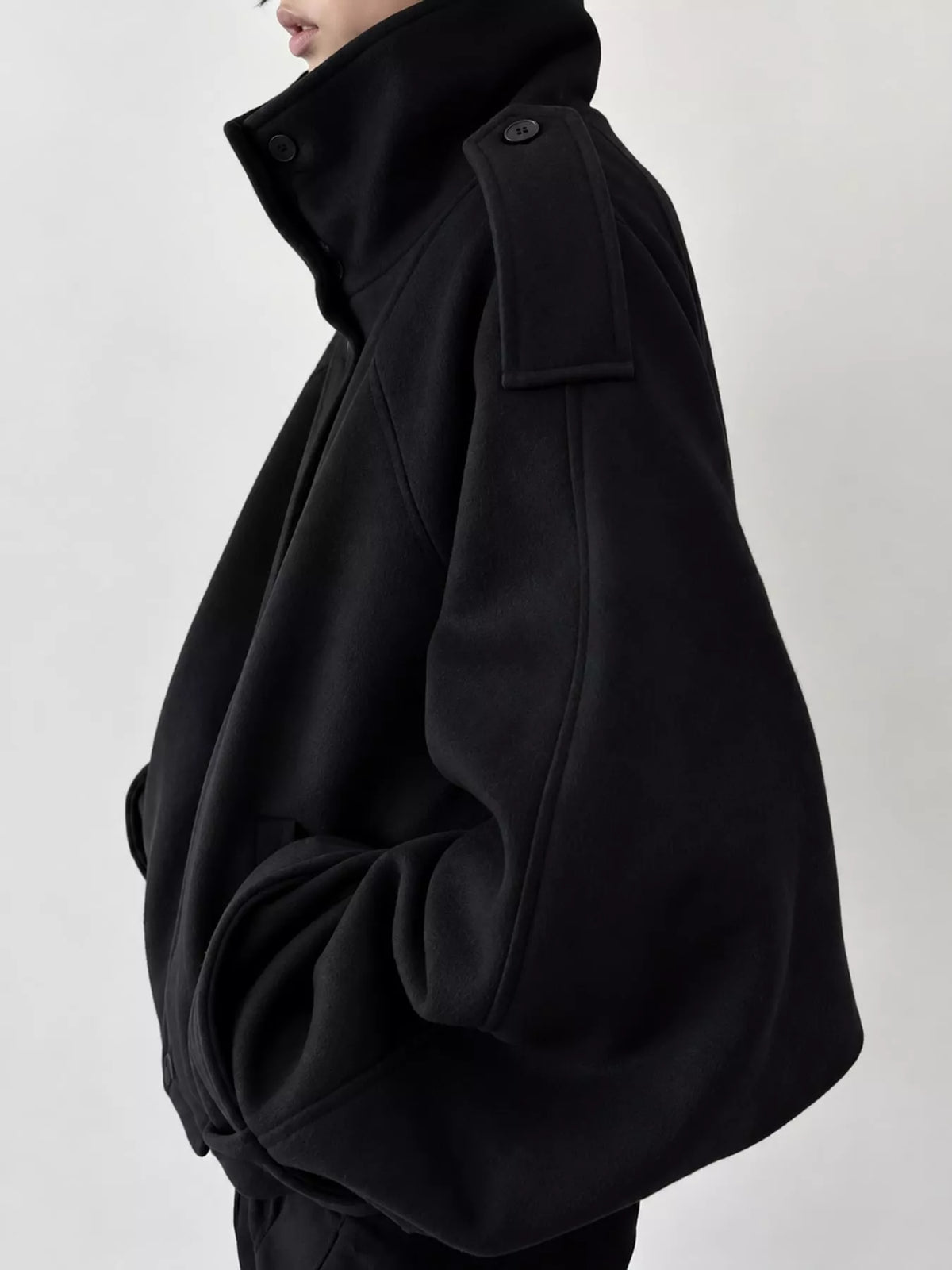 Black stand-collar zip-up jacket, side view with dropped shoulder and cuff snaps.