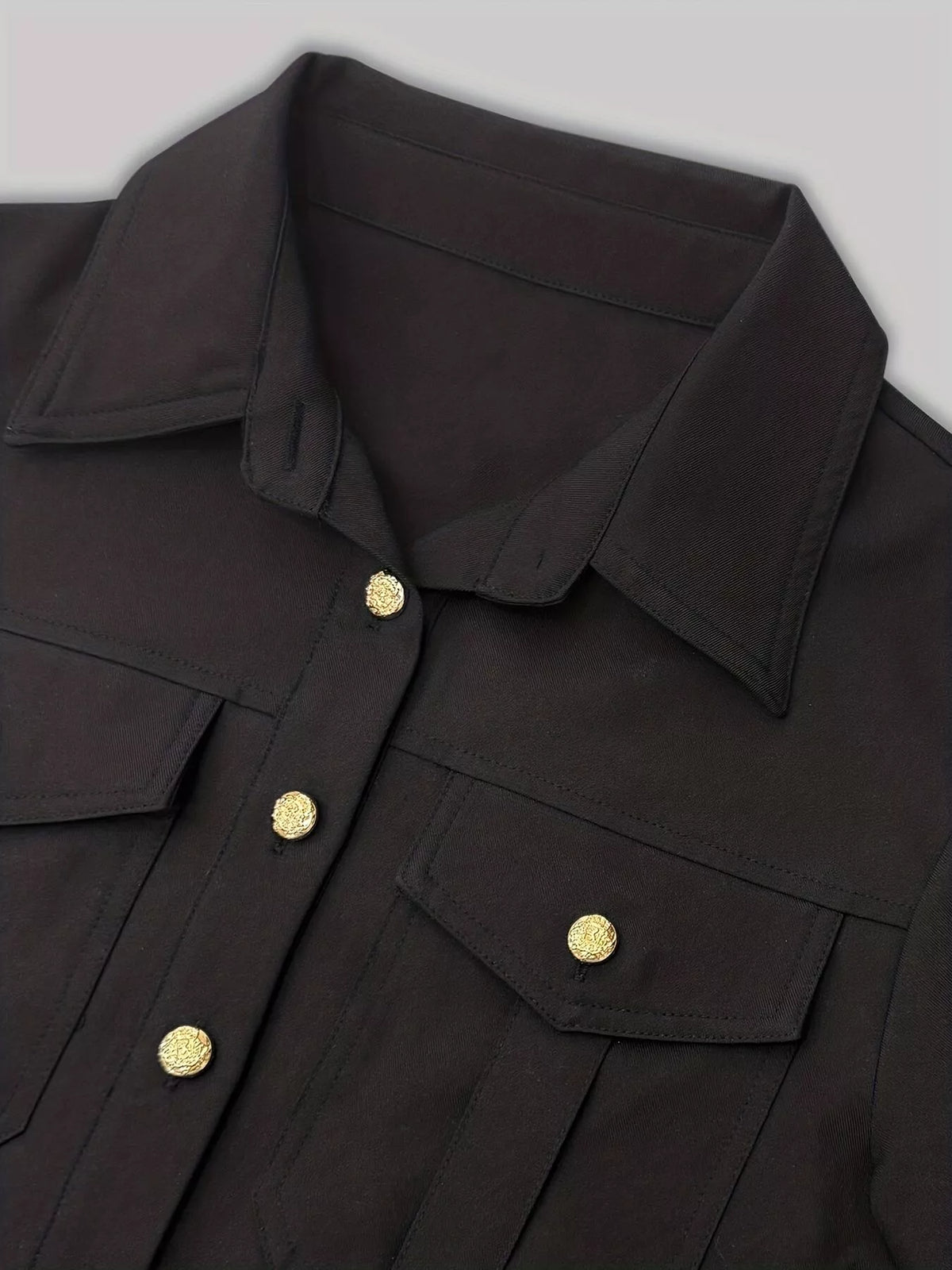 Black button-front long sleeve midi dress close-up with collar, flap pockets, and gold buttons